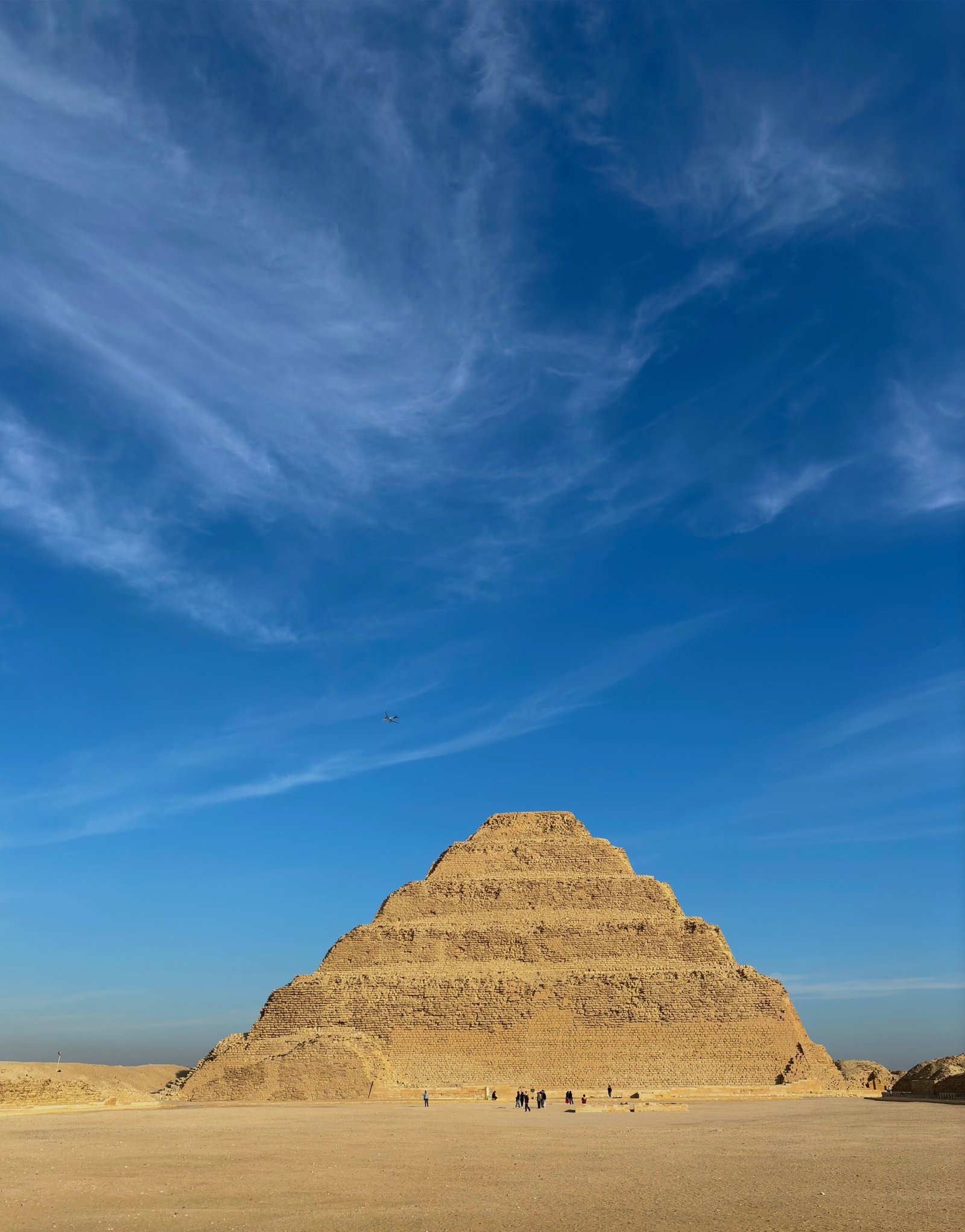 The ancient Step Pyramid of Djoser under a vibrant blue sky in Egypt.